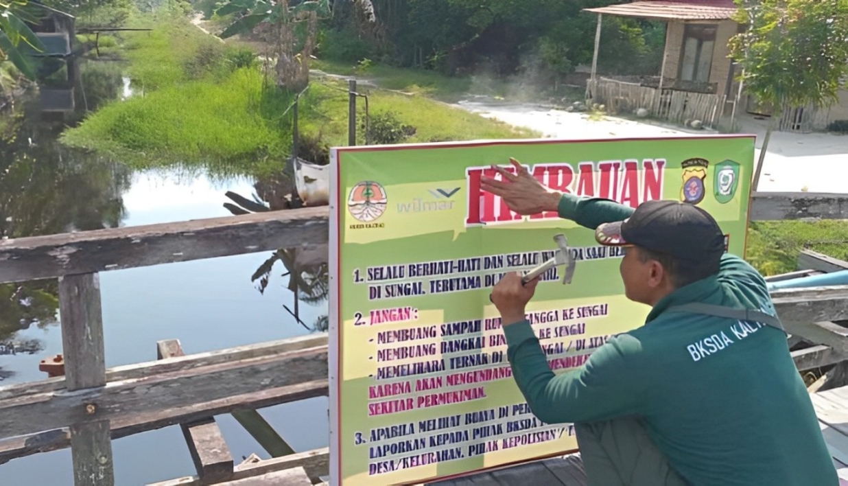 <p>Komandan BKSDA Pos Jaga Sampit, Muriansyah saat memasang papan peringatan keberadaan buaya di Kecamatan Teluk Sampit, belum lama ini.</p>
