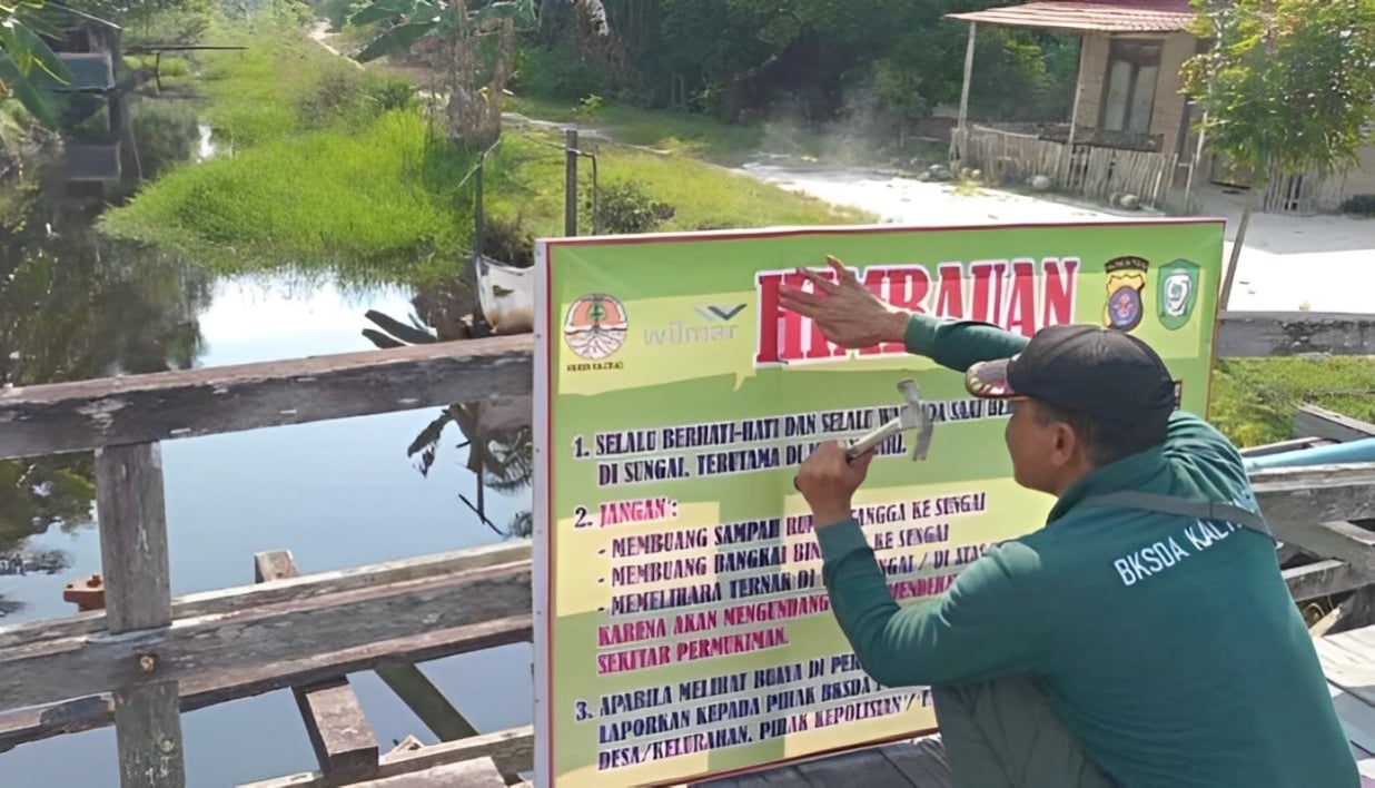<p>Komandan BKSDA Pos Jaga Sampit, Muriansyah saat memasang papan peringatan keberadaan buaya di Kecamatan Teluk Sampit, belum lama ini.</p>