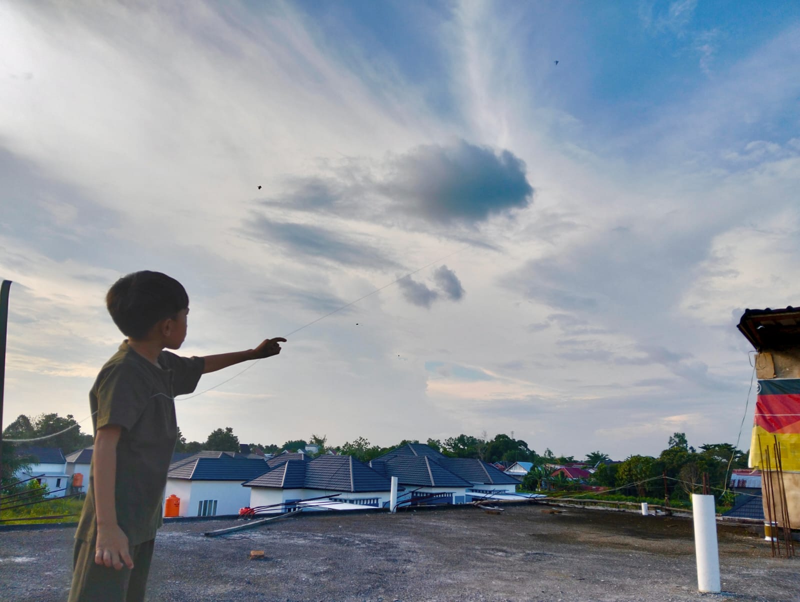 <p>Salah satu anak di Sampit sedang bermain layangan diatas atap rumahnya, Kamis (17/7/2025). (Foto: Apri) </p>